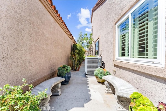 view of side of home featuring cooling unit, a patio area, and stucco siding