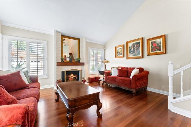 living area with baseboards, wood finished floors, high vaulted ceiling, and a fireplace