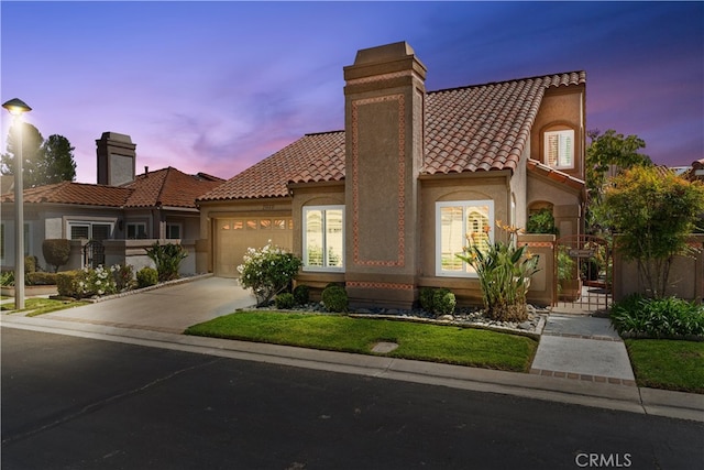 mediterranean / spanish home with a tiled roof, a chimney, a garage, concrete driveway, and stucco siding