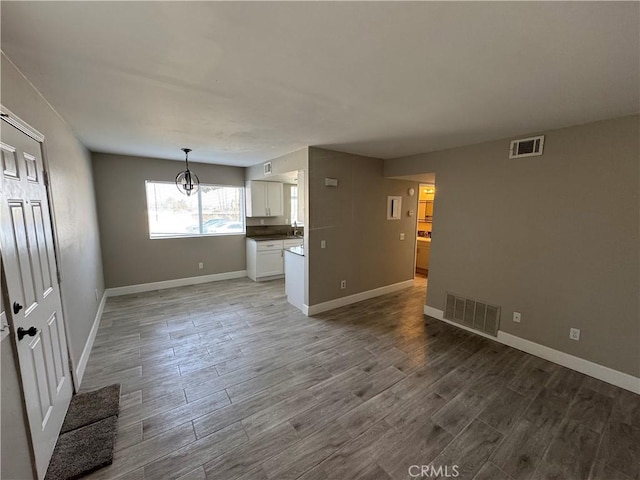 unfurnished living room with baseboards, visible vents, and wood finished floors