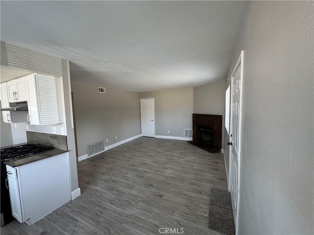 unfurnished living room featuring baseboards, a fireplace, and visible vents
