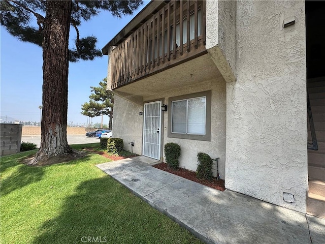 view of exterior entry featuring a lawn and stucco siding