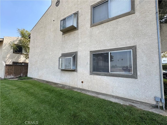 view of side of property with stucco siding and a yard