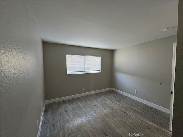 unfurnished room featuring baseboards and wood finished floors