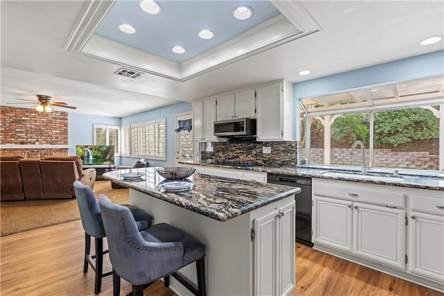 27118 Highlands Ln, Valencia, CA 91354 - kitchen featuring black dishwasher, a sink, a raised ceiling, a kitchen bar, and dark stone counters