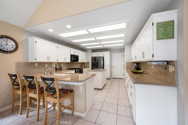 315 Alder St, Arroyo Grande, CA 93420 - kitchen with decorative backsplash, a peninsula, a sink, light tile patterned floors, and black appliances