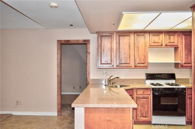 kitchen featuring a sink, a peninsula, baseboards, light tile patterned floors, and gas range oven