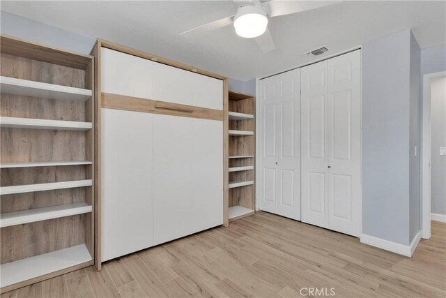 unfurnished bedroom with a ceiling fan, visible vents, baseboards, two closets, and light wood finished floors