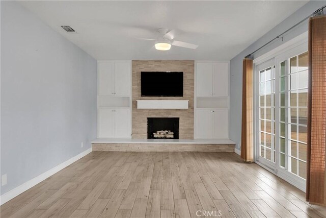 unfurnished living room featuring light wood-style floors, baseboards, ceiling fan, and a large fireplace