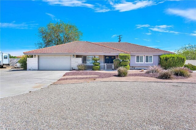 single story home with an attached garage, a tile roof, stucco siding, a porch, and concrete driveway