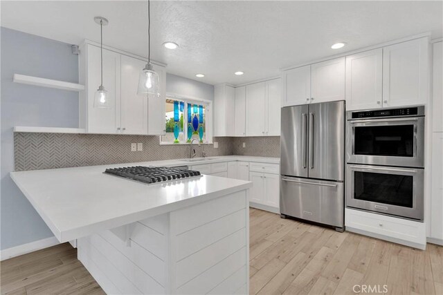 kitchen featuring white cabinets, open shelves, appliances with stainless steel finishes, a sink, and backsplash