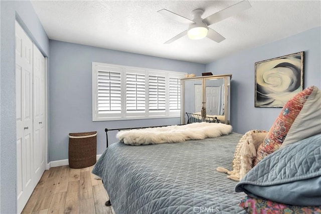 bedroom with a textured ceiling, a ceiling fan, baseboards, hardwood / wood-style flooring, and a closet