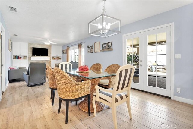 dining space with visible vents, french doors, ceiling fan with notable chandelier, and light wood-type flooring