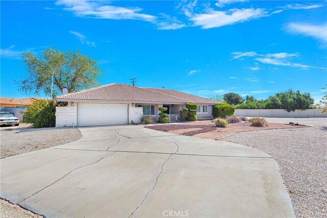 ranch-style home featuring a garage, fence, stucco siding, a tiled roof, and driveway