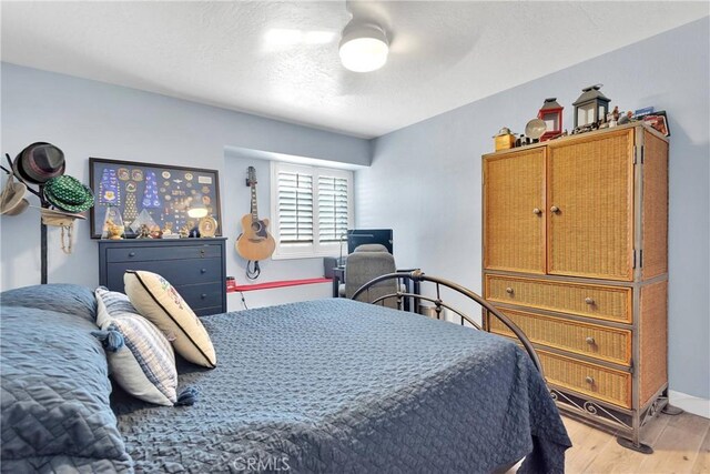 bedroom featuring baseboards, a ceiling fan, and light wood-style flooring