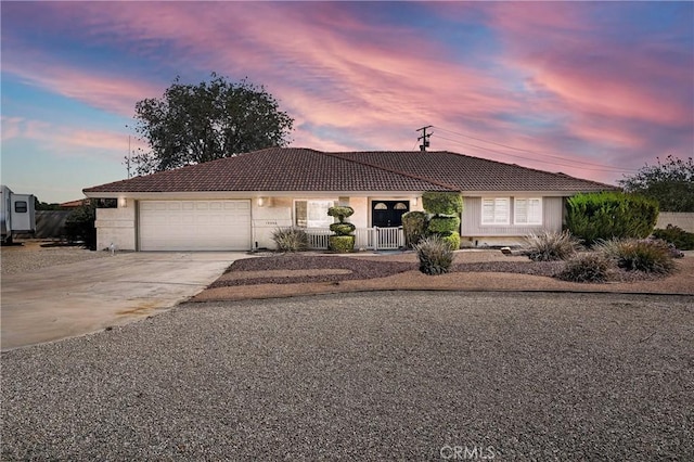 ranch-style home with an attached garage, driveway, a tile roof, and stucco siding