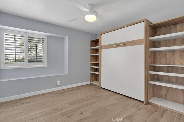 unfurnished bedroom featuring light wood-style floors, baseboards, ceiling fan, and a closet