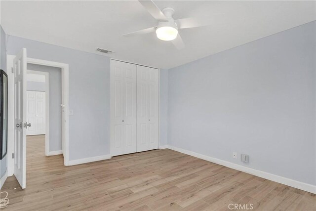 unfurnished bedroom with baseboards, visible vents, light wood-style flooring, and a closet
