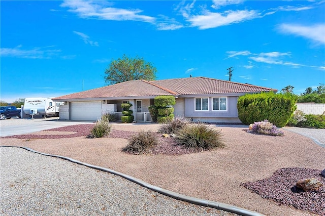 ranch-style house featuring an attached garage, driveway, and a tile roof