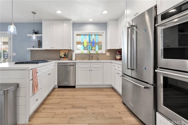 kitchen with open shelves, decorative backsplash, white cabinets, a sink, and appliances with stainless steel finishes