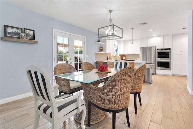 dining space featuring french doors, visible vents, light wood-type flooring, baseboards, and a notable chandelier