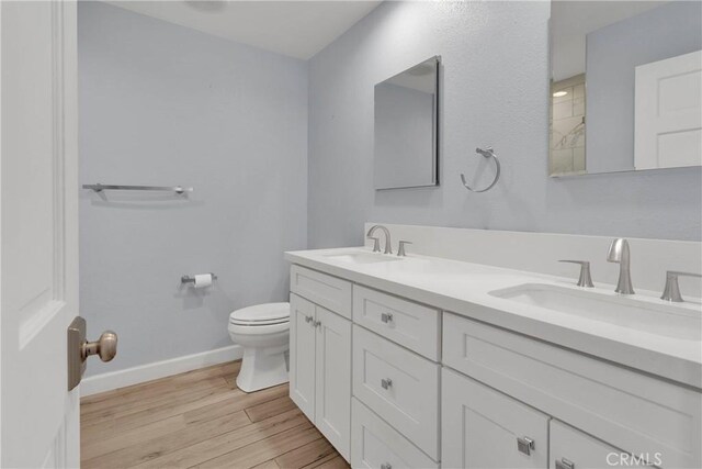 bathroom with baseboards, a sink, wood finished floors, and toilet