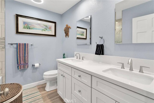 bathroom featuring a sink, baseboards, toilet, and wood finished floors