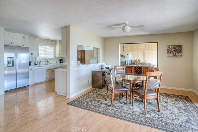 dining area with light wood-style floors, baseboards, and a ceiling fan