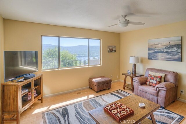 living area featuring baseboards, a ceiling fan, a mountain view, and wood finished floors