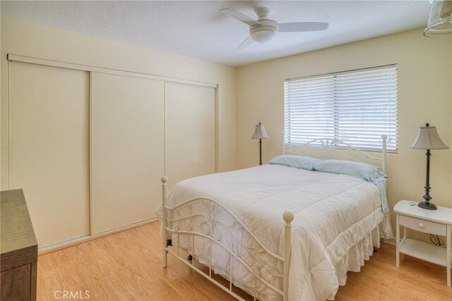 bedroom with a ceiling fan, light wood finished floors, and a closet