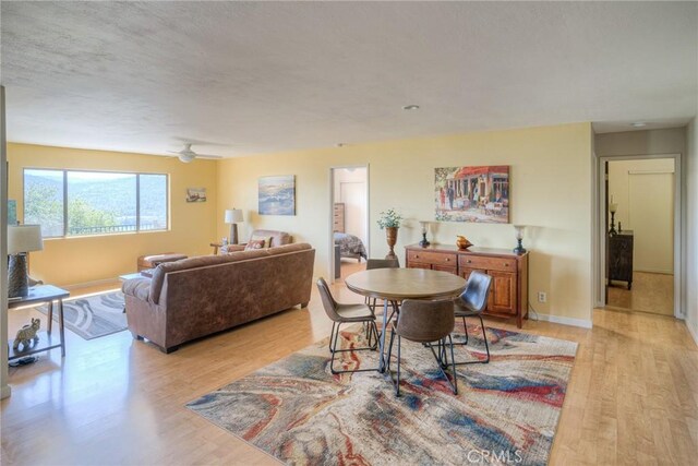 dining room featuring baseboards, ceiling fan, and light wood-type flooring