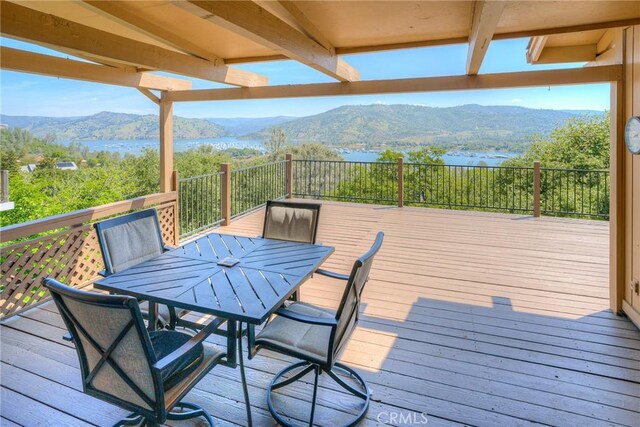 wooden deck featuring outdoor dining space and a water and mountain view