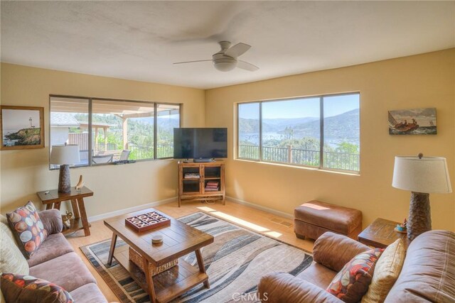 living area with baseboards, visible vents, and ceiling fan