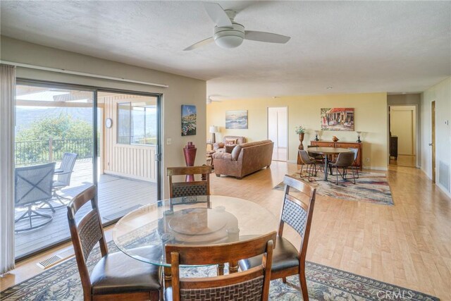dining room featuring baseboards, ceiling fan, visible vents, and light wood-style flooring