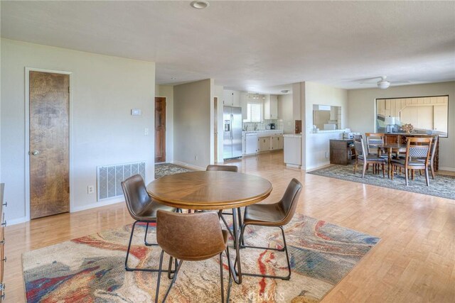 dining space with visible vents, light wood-style floors, ceiling fan, and baseboards