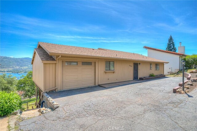 ranch-style house with a garage, a mountain view, a chimney, and aphalt driveway