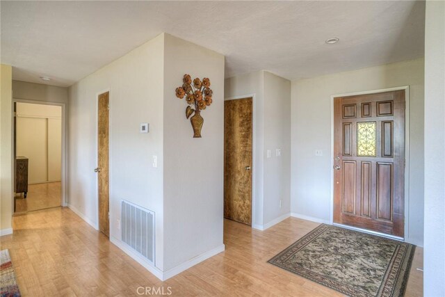 foyer featuring baseboards, visible vents, and light wood-type flooring