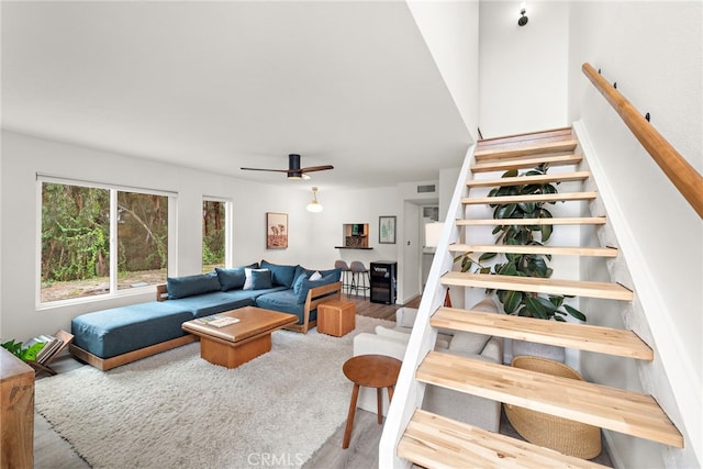 living room with a ceiling fan, wood finished floors, and stairway