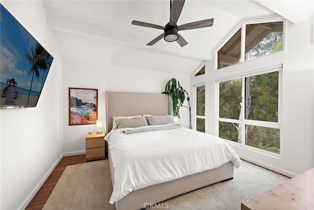 bedroom with ceiling fan, baseboards, vaulted ceiling with beams, and wood finished floors