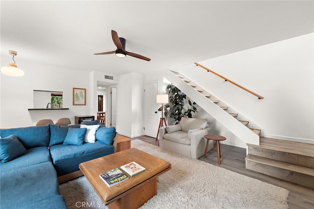 living area featuring visible vents, stairs, wood finished floors, baseboards, and a ceiling fan