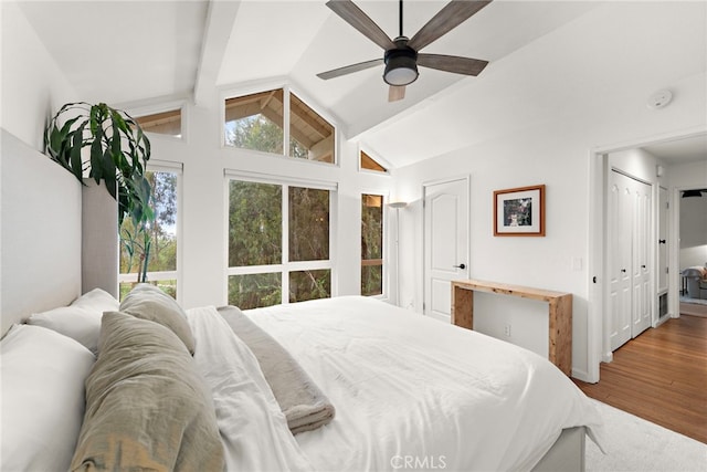 bedroom with lofted ceiling with beams, a ceiling fan, and wood finished floors