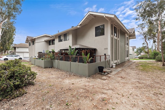 view of property exterior with a gazebo, stucco siding, and fence