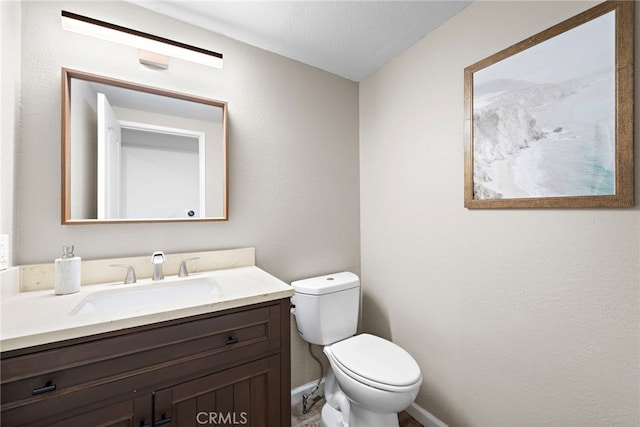 bathroom with vanity, baseboards, and toilet