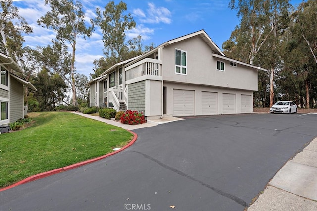 view of side of home featuring driveway, a lawn, stairway, an attached garage, and stucco siding