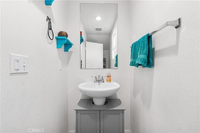 bathroom with baseboards, visible vents, and a sink