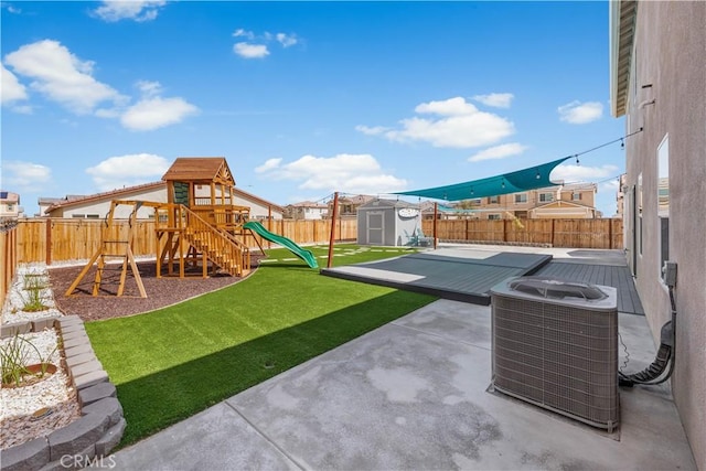 view of yard with a patio, a fenced backyard, central AC unit, a playground, and a storage shed
