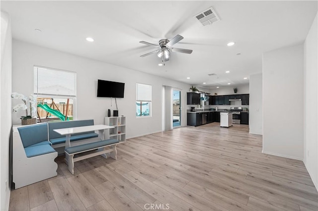 living room featuring a ceiling fan, visible vents, baseboards, light wood-style floors, and recessed lighting