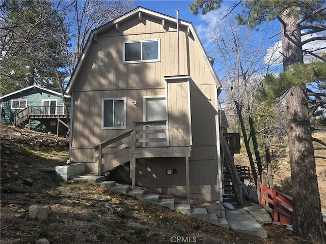 back of property featuring a deck, a gambrel roof, and stairway