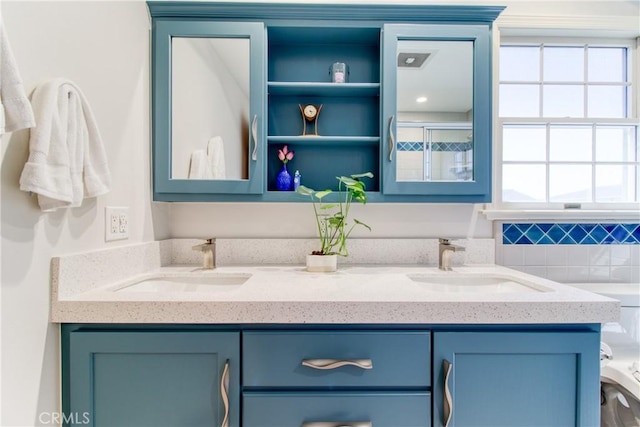 full bathroom featuring double vanity, a sink, and a shower with shower door