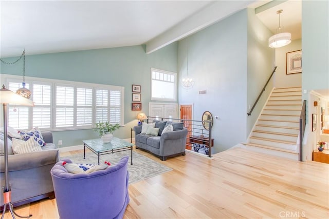 living area featuring stairway, high vaulted ceiling, wood finished floors, and a notable chandelier